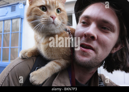 Große Thema Anbieter mit seinem Haustier Katze 'Bob' auf seiner Schulter stationiert schnappte beiläufig zu Fuß nach unten Shelton Street, Covent Garden. Stockfoto