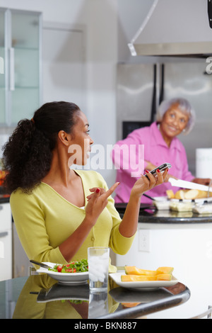 Afroamerikanische Frau Salat essen und reden über Handy Stockfoto