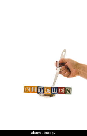 Frau mit einer Kelle hält Kinder Blöcke, die "Küche" buchstabieren Stockfoto