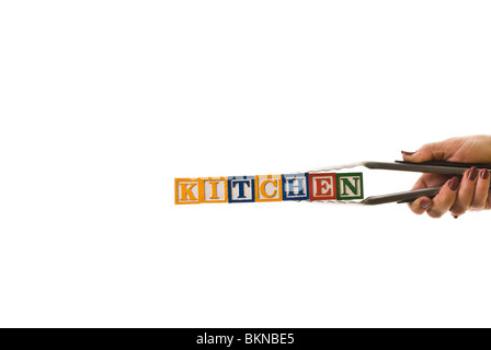 Frau mit einer Zange halten Kinder Blöcke, die "Küche" buchstabieren Stockfoto