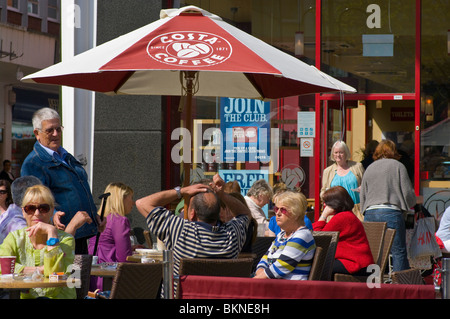 Menschen entspannen zusammen am Tische draußen ein Costa-Kaffee Stockfoto