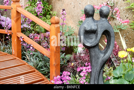 wo geleitet, Statue, japanische Wetter Stil Holzbrücke, Aubrieta Hebe Magie Sommer, Ilex X altaclerensis 'Golden King' weibliche holly Stockfoto