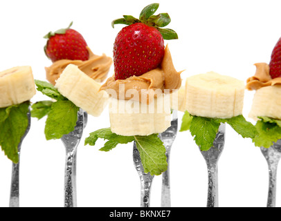 Bananenscheiben, Erdnussbutter und ganze Erdbeeren auf Gabeln mit Minze. Stockfoto