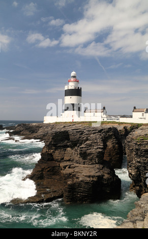 Der Haken Leuchtturm auf der Halbinsel Hook, Co Wexford, Irland betrachtet von Felsen neben der Klippenpfad. Stockfoto