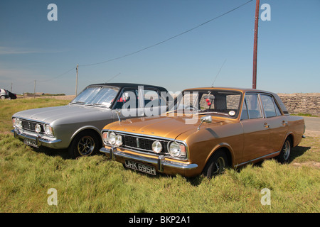 Zwei 4 Türen Ford Cortina Mark II Oldtimer parkten in der Nähe von Hook Lighthouse auf der Halbinsel Hook, Wexford, Irland. Stockfoto