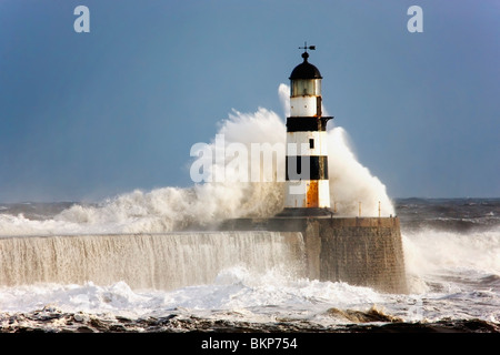 Seaham, Teesside, England; Wellen, die gegen ein Leuchtturm Stockfoto