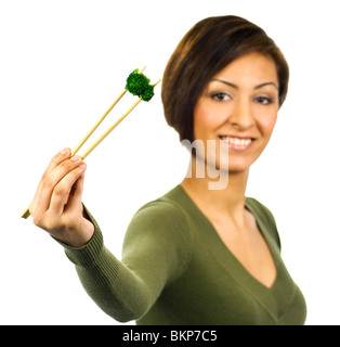 Lächelnde Dame hält ein grünes Stück gekochten Brokkoli mit Stäbchen. Stockfoto