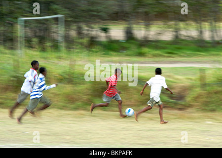 Afrikanische Kinder Fußballspielen barfuß in einem Feld in Hout Bay in Cape Town, Südafrika. Stockfoto