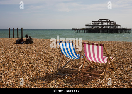 Brighton Kies Strand Liegestühle und zerstörten West Pier. Stockfoto