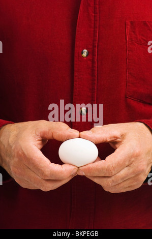 Mann hält ein weißes Ei Stockfoto