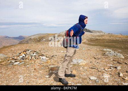 Man lehnt sich dem Wind an einem sehr windigen Tag auf exponierte Berggipfel der Glyder Fawr im Snowdonia National Park North Wales UK Stockfoto