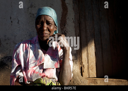 Malawi, Lilongwe, Ntchisi Waldreservat. Eine alte Frau sitzt am Eingang zu ihrer Hütte in einem Bergdorf. Stockfoto