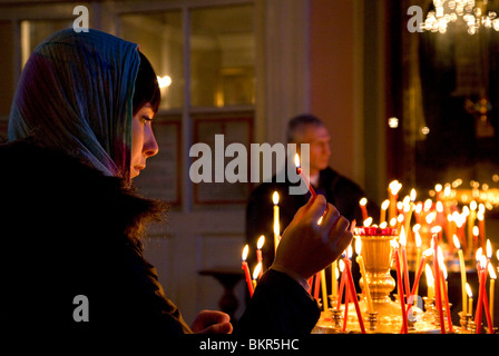 Russland, St.Petersburg; Ein Mädchen, das Anzünden einer Kerze kurz vor der orthodoxen Zeremonie zu Vladimirsky Kathedrale Stockfoto