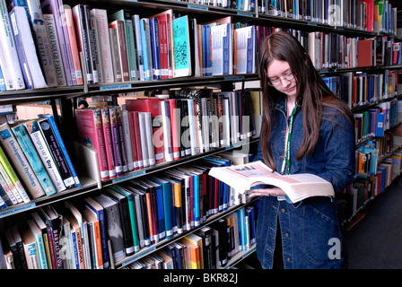Studentin in College-Bibliothek mit Bücherregalen Stockfoto