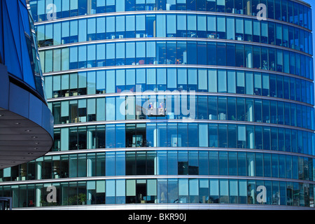 Zwei Männer in einer Fensterreinigung Wiege Waschen der Glasuren Wand von einem Bürogebäude in London Stockfoto