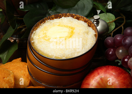 Schale mit heißer Grütze und Butter mit Gebäck und Obst in der Küche. Stockfoto