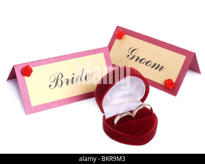 Trauringe in rotem Wildleder-Box und Braut und Bräutigam Namenskarten über weiß Stockfoto