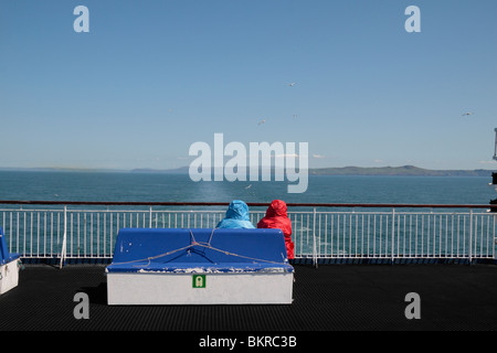 Zwei Passagiere sitzen auf einem blauen Bank nahe an die auf dem Heck der Stena Europa Autofähre, an der irischen See. Stockfoto