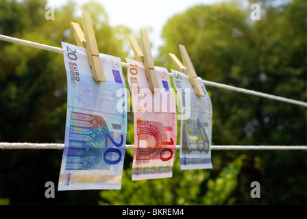 Drei Euro-Scheine auf einer Wäscheleine mit hölzernen Wäscheklammern, als Symbol für "Geldwäsche" hängen. Im Mittelpunkt der 20 Euro-Schein. Stockfoto