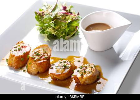 Jakobsmuscheln mit Salat und Sauce auf weißen Teller Stockfoto