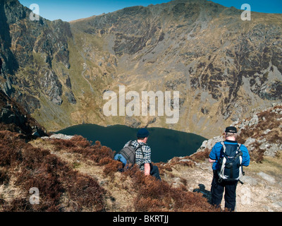 Zwei männliche Rucksacktouristen Blick auf Lake Cau mit den Hängen des Cader Idris steil steigt im Hintergrund ruht Stockfoto