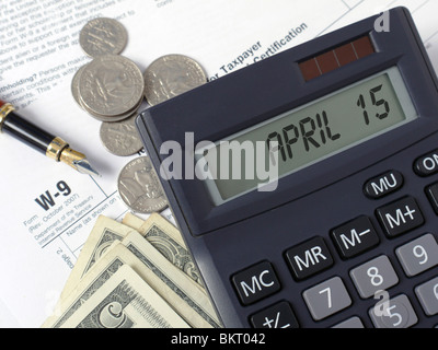 Taschenrechner mit lcd Anzeige 15 April mit Stift und US-Dollar auf w-9 Einkommensteuer Formen gelegt. Stockfoto