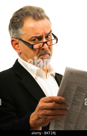 Ein reifer Mann mit Brille liest seine Zeitung mit einem entsetzt Blick auf seinem Gesicht. Stockfoto