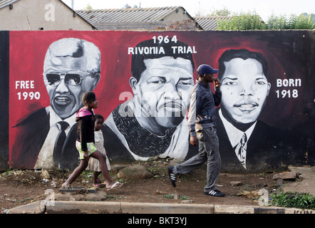 Kinder, vorbei an einem Wandbild Nelson Mandela im Township Soweto, Johannesburg, Südafrika Stockfoto