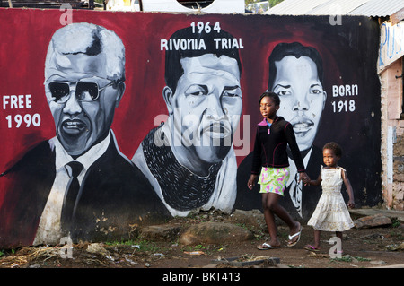 Kinder, vorbei an einem Wandbild Nelson Mandela im Township Soweto, Johannesburg, Südafrika Stockfoto