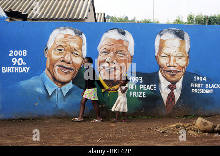 Kinder, vorbei an einem Wandbild Nelson Mandela im Township Soweto, Johannesburg, Südafrika Stockfoto