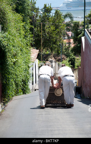 Einem geflochtenen Korb Rodel Schlitten wird von zwei Carreiros gesteuert de Monte. Stockfoto