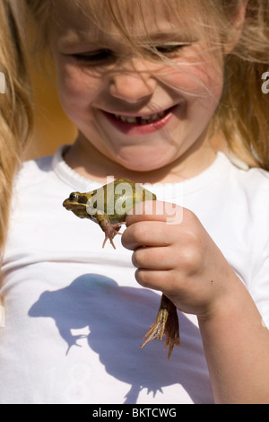 Meisje traf Schlittschuhläufer Kikker; Mädchen mit Grasfrosch Stockfoto