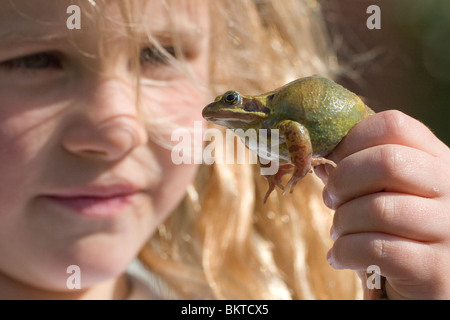 Meisje traf Schlittschuhläufer Kikker; Mädchen mit Grasfrosch Stockfoto