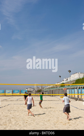 Menschen spielen Beach-Volleyball auf Sand am Meer auf Brighton Seafront in warmem Wetter und blauem Himmel Stockfoto