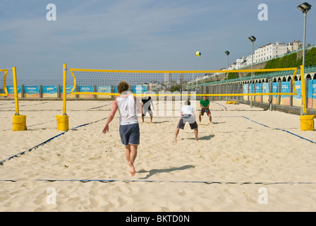 Menschen spielen Beach-Volleyball auf Sand am Meer auf Brighton Seafront in warmem Wetter und blauem Himmel Stockfoto