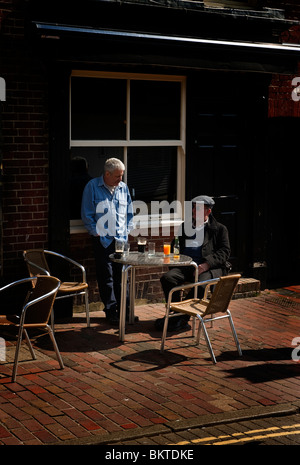 Zwei mittleren Alters männlichen Erwachsenen Männern sitzen am Tisch und Stühle vor einem Pub Brighton Stockfoto
