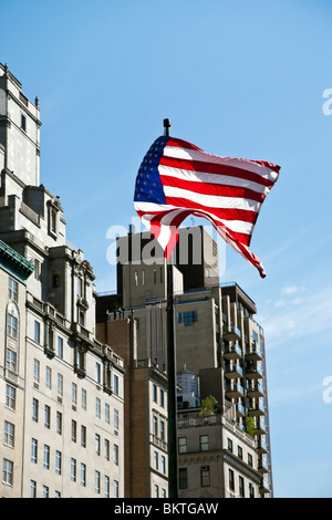 Amerikanische Flagge fliegt unbeschwert in eine steife Brise vor Hintergrund des blauen Himmels & teure oberen Fifth Avenue Immobilien Manhattan Stockfoto