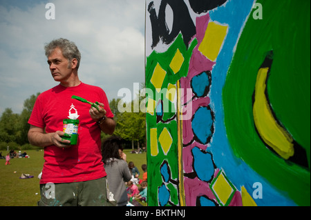 "Fairer Handel" Welttag, Mann Malerei Wand, auf Rasen "La Villette" Park Kauf fairer Handel fördern Stockfoto