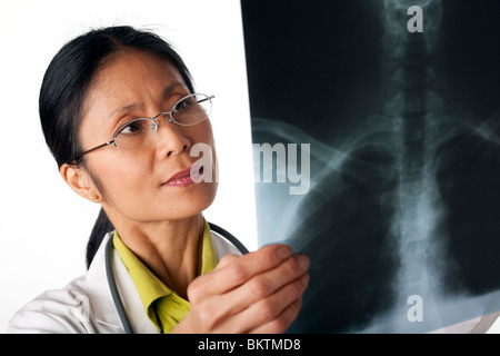 Asiatische Ärztin Blick auf eine Röntgenaufnahme der Lunge. Horizontalen Schuss. Isoliert auf weiss. Stockfoto