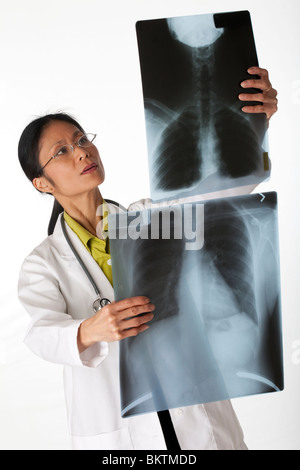 Erhöhte Ansicht eines asiatischen weiblichen Arzt Blick auf Röntgen der Lunge. Vertikale erschossen. Isoliert auf weiss. Stockfoto