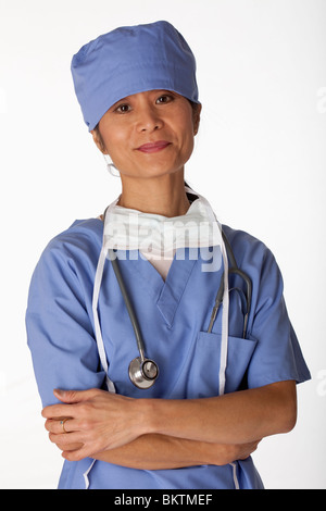 Porträt von einem asiatischen weiblichen Arzt tragen scheuert. Sie ist in die Kamera schaut und hat ihre Arme verschränkt. Vertikal Stockfoto