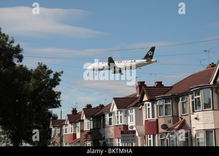 Ein Star Alliance Airbus A320-232 landet auf dem Flughafen Heathrow, London, UK. Ansicht von Myrtle Avenue, Hounslow. (G-MIDX) Stockfoto