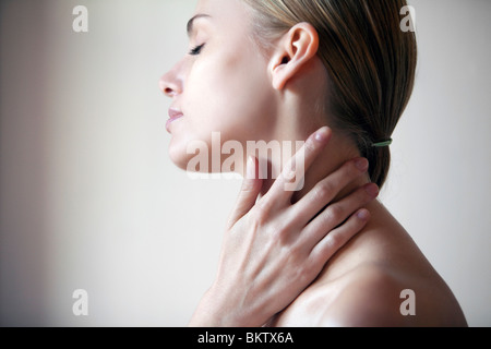 Junge Frau mit den Händen auf Hals, Augen geschlossen Stockfoto