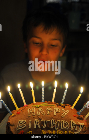 Ein zehn Jahre alter Junge bläst die Kerzen seiner Geburtstagstorte Stockfoto