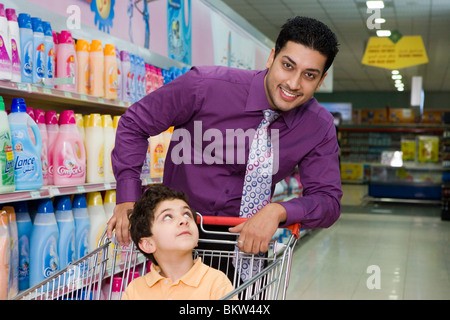 Vater mit Sohn sitzen im Einkaufswagen im Supermarkt, Porträt Stockfoto