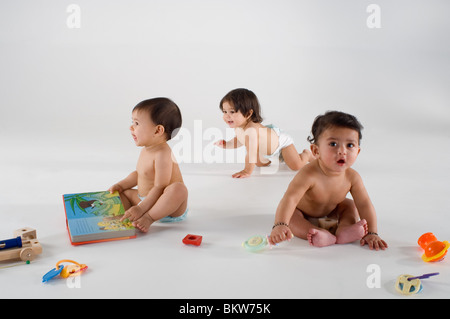 Drei Babys sitzen spielen mit Spielzeug Stockfoto