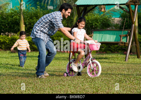 Tochter lernen Fahrrad mit ihrem Vater, Sohn, jagen Stockfoto