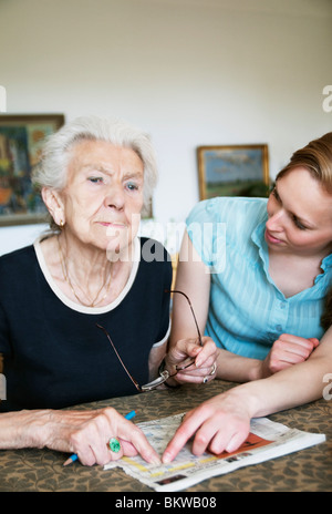 Ältere Dame, die durch Reflexion Tisch sitzen Stockfoto