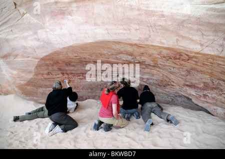 Reisende, die neolithische Felskunst in der Foggini-Mestikawi Cave, im Wadi Sura in der Gilf Kebir Region der Sahara (West) Wüste in Ägypten untersuchen. Stockfoto