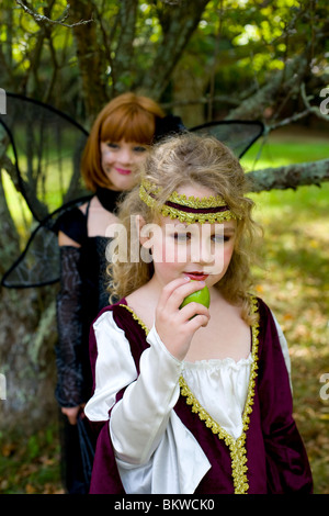 Ein junges Kind nimmt einen Apfel von einer schwarzen Fee Stockfoto